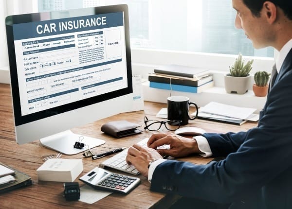 Man completing auto insurance form on computer at desk