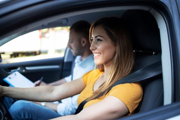 Driving instructor with a checklist in the car with a new driver student