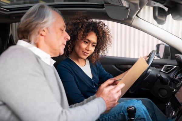 Woman discussing auto insurance with an agent inside a car