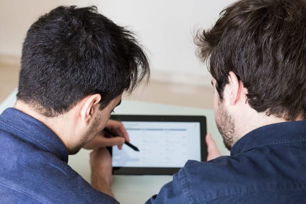 Two people reviewing auto insurance comparison results on a tablet screen