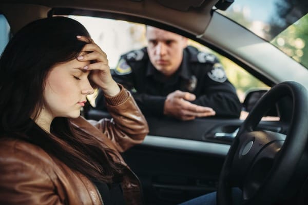 Driver being stopped by a police officer during a traffic stop after suspected DUI while sitting in the driver's seat of a car