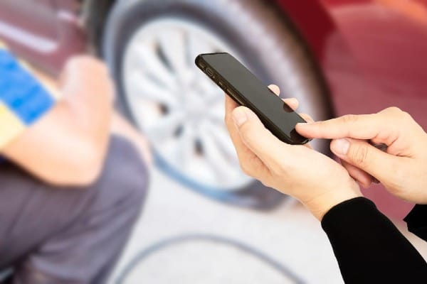 Person filing an auto insurance claim on a mobile app after a car accident